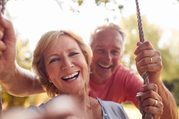 Portrait Retired Couple Having Fun Man Pushing Woman Garden Swing — Stok Foto