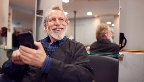 Senior Man Wachtend Haar Knippen Kapsalon Zoek Naar Mobiele Telefoon — Stockfoto