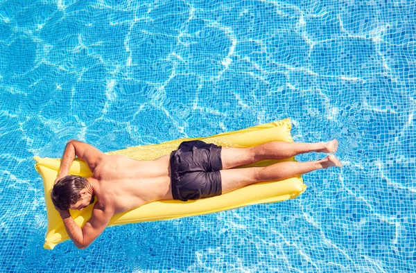 男子在游泳池中的头顶射击 在室外游泳池的空气床上漂浮 夏天度假 — 图库照片