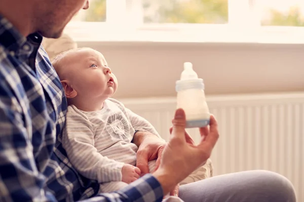 Vater Füttert Baby Sohn Mit Flasche Auf Stuhl Wohnzimmer — Stockfoto