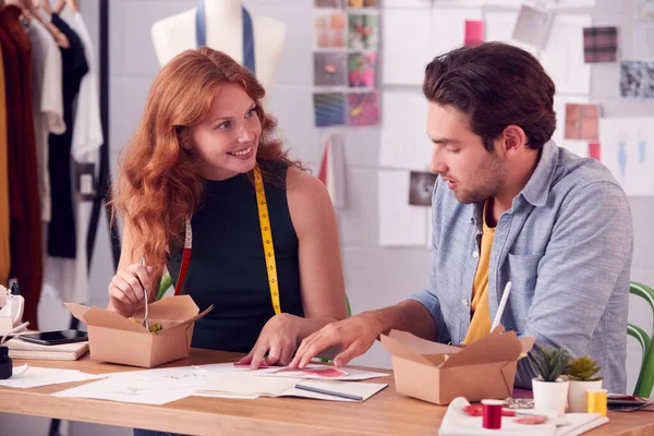 男性と女性のファッションビジネスオーナーがスタジオでテイクアウトフードのデザインについて話し合う — ストック写真