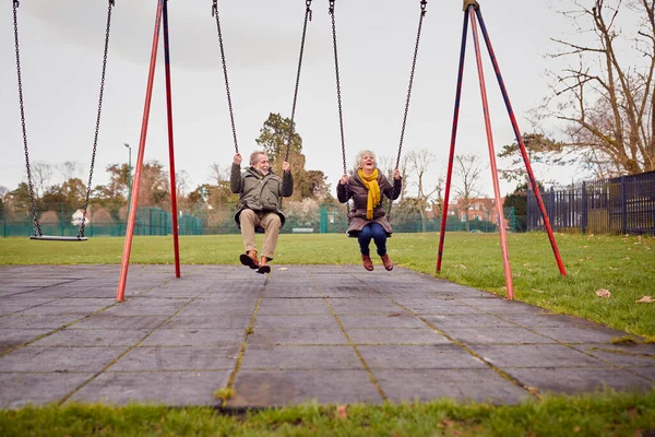 Ηλικιωμένο Ζευγάρι Που Διασκεδάζουν Παίζοντας Στις Αιώρες Στο Πάρκο Παιδική — Φωτογραφία Αρχείου