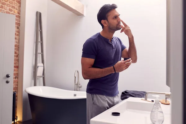 Homem Vestindo Pijama Casa Banheiro Moderno Colocando Hidratante Olhando Espelho — Fotografia de Stock