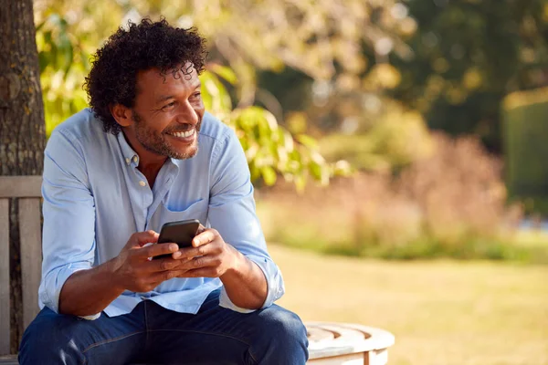 Reifer Mann Sitzt Mit Handy Auf Bank Unter Baum Sommerpark — Stockfoto