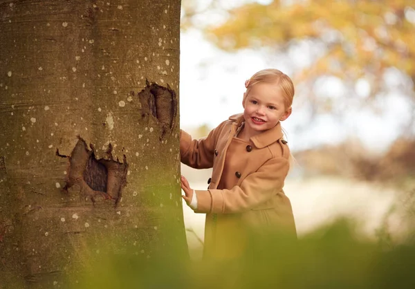 Genç Kız Sonbahar Ağacının Gövdesine Bakıp Bahçede Saklambaç Oynuyor — Stok fotoğraf