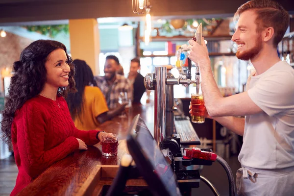 Glimlachende Mannelijke Barman Achter Balie Serveren Vrouwelijke Klant Met Bier — Stockfoto