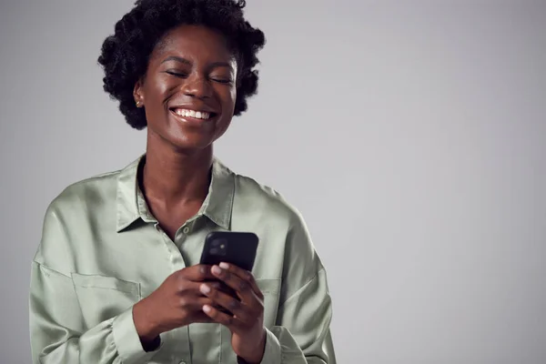 手机在简朴背景下微笑的年轻女商人的工作室肖像 — 图库照片