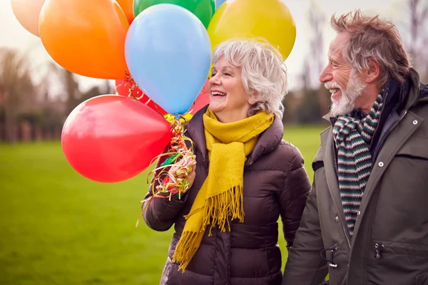 Kochająca Para Starszych Holding Balony Cieszący Się Jesienią Lub Zimą — Zdjęcie stockowe