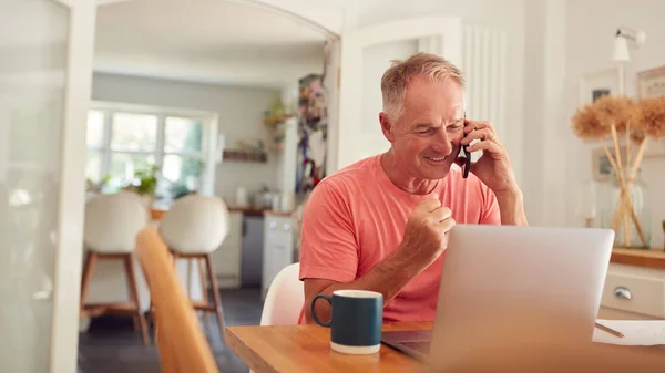 Homem Aposentado Telefone Casa Cozinha Usando Laptop Celebrando Boas Notícias — Fotografia de Stock