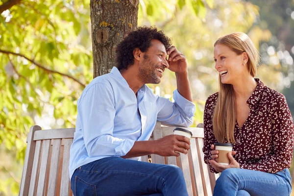 コーヒーと一緒に夏の公園で木の下のベンチで一緒に座ってリラックスした成熟したカップルを愛し — ストック写真