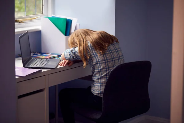健康中にノートパソコンで自宅学習中に机の上に寝そべって座っている退屈した女の子パンデミック — ストック写真