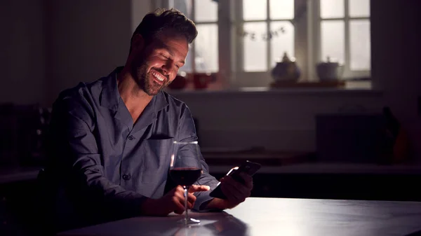 Man Wearing Pyjamas Sitting Kitchen Glass Wine Night Using Mobile — Fotografia de Stock