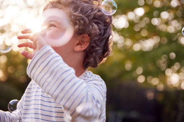 Menino Divertindo Jardim Perseguindo Rebentando Bolhas — Fotografia de Stock