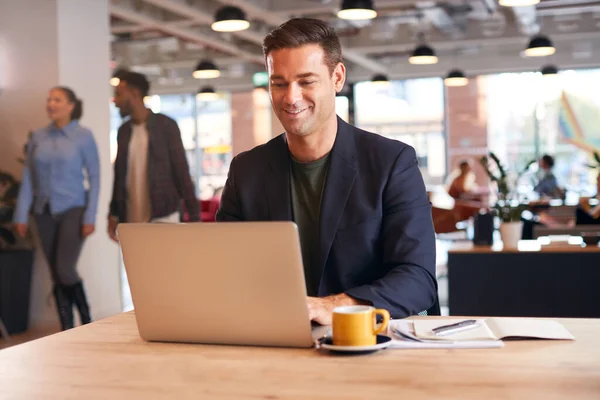 Biznesmen Siedzi Przy Biurku Pracuje Laptopie Nowoczesnym Biurze Open Plan — Zdjęcie stockowe