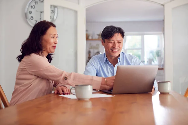 家庭の請求書や金融を整理するためにラップトップを使用して自宅で成熟したアジアのカップル — ストック写真