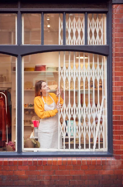 女性の中小企業経営者がセキュリティグリルを押し返し 店を開く — ストック写真