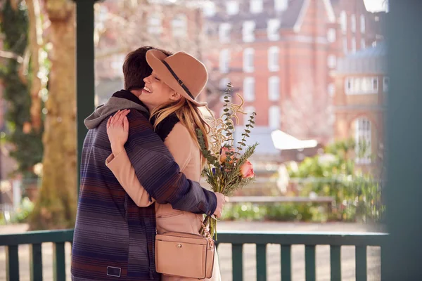 Romantiker Mann Umarmt Junge Frau Nachdem Ihr Einen Blumenstrauß Geschenkt — Stockfoto