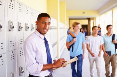 Male Teacher Standing By Lockers clipart