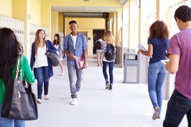 Group Of Students Walking Along Hallway clipart