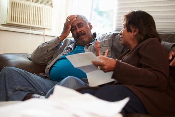 Bezorgd Senior paar zittend op de bank kijken naar rekeningen — Stockfoto