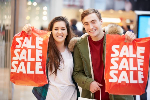 Pareja feliz llevando bolsas en el centro comercial — Foto de Stock