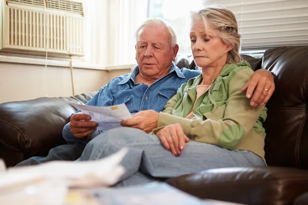 Couple âgé inquiet assis sur le canapé regardant les projets de loi — Photo