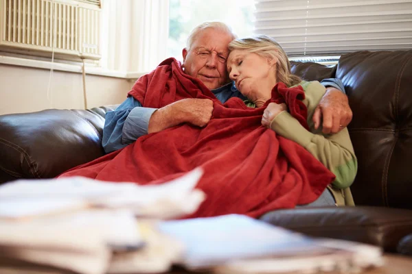 Coppia anziana che cerca di mantenere caldo sotto coperta a casa — Foto Stock