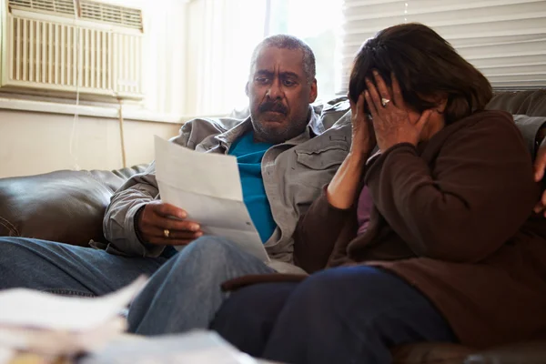 Oroliga äldre paret sitter på soffan tittar på räkningar — Stockfoto