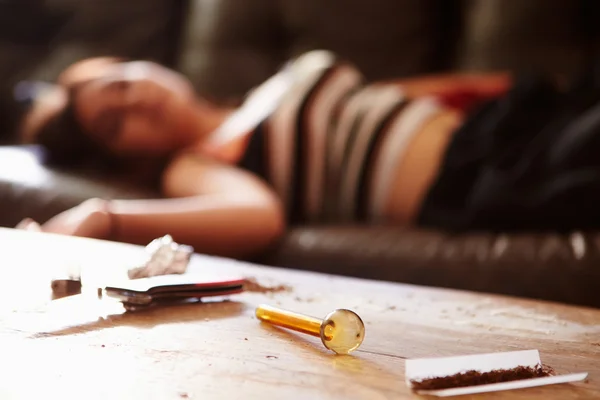 Frau mit Drogen-Utensilien im Vordergrund auf Sofa zusammengebrochen — Stockfoto