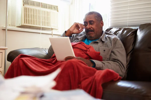 Senior homem mantendo quente sob cobertor com fotografia — Fotografia de Stock