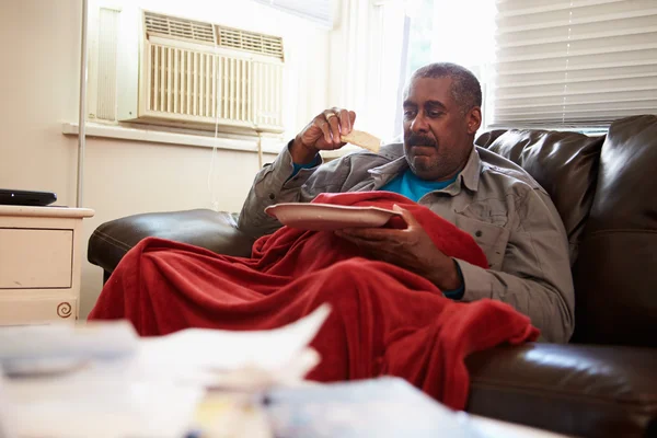 Starší muž s nevhodnou stravou, udržování teploty pod dekou — Stock fotografie