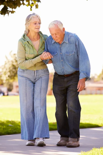 Seniorin hilft Ehemann beim gemeinsamen Spaziergang im Park — Stockfoto