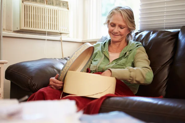 Senior vrouw Warm onder deken met geheugen doos houden — Stockfoto