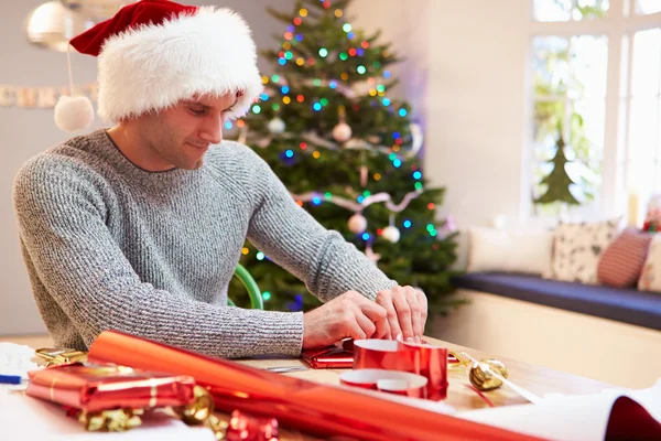 Homem embrulhando presentes de Natal em casa — Fotografia de Stock