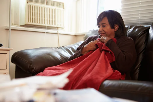 Senior mulher tentando manter quente sob cobertor em casa — Fotografia de Stock