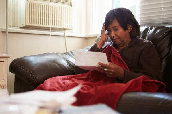 Ανησυχούν ανώτερος γυναίκα που κάθεται στον καναπέ, κοιτάζοντας τους λογαριασμούς — Φωτογραφία Αρχείου