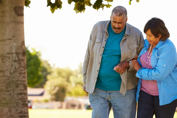 Seniorin hilft Ehemann beim gemeinsamen Spaziergang im Park — Stockfoto