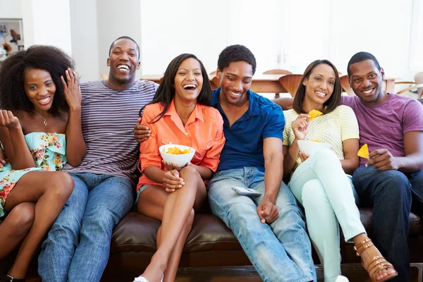 Grupo de amigos sentados en el sofá viendo televisión juntos — Foto de Stock