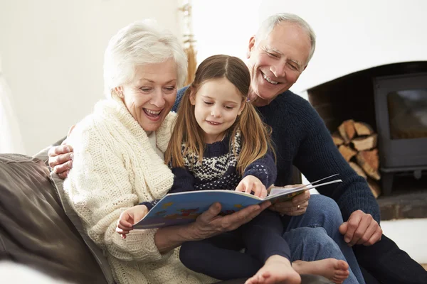 Grootouders en de kleindochter lezen van boek — Stockfoto