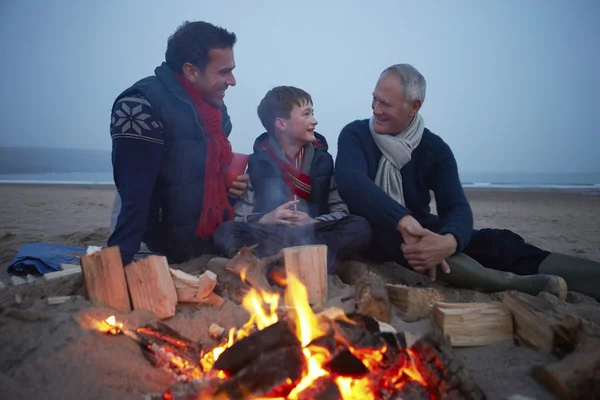 Familia multi-generación sentada junto al fuego — Foto de Stock