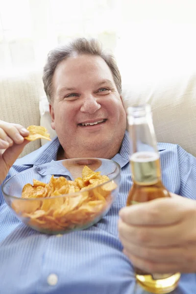 Homem comendo batatas fritas e bebendo cerveja — Fotografia de Stock