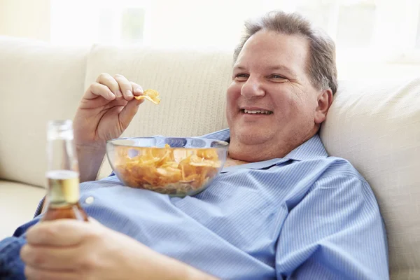 Homem comendo batatas fritas e bebendo cerveja — Fotografia de Stock