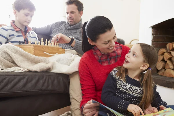 Familia jugando al ajedrez y leyendo libro — Foto de Stock