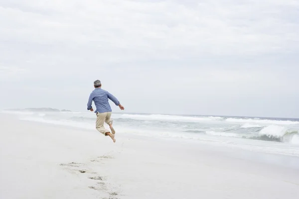 Senior man springen op strand — Stockfoto