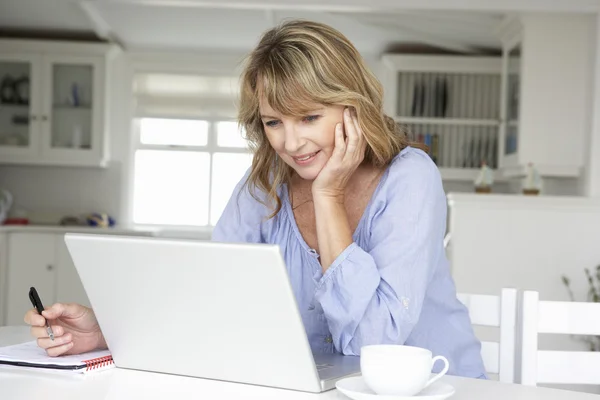 Midden leeftijd vrouw die op laptop werkt — Stockfoto