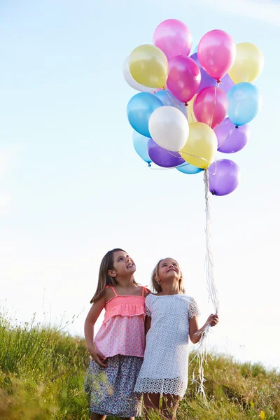 Unga tjejer hålla ballonger — Stockfoto