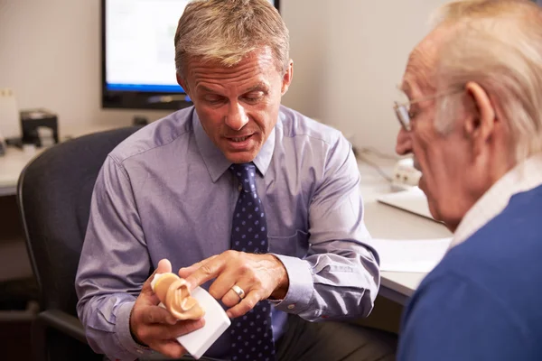 Доктор показывает пациенту модель уха — стоковое фото