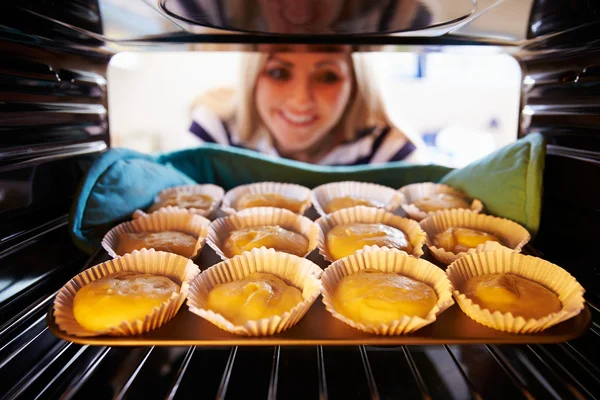 Kvinna att sätta Cupcakes till baka — Stockfoto