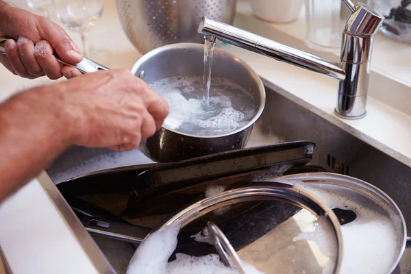 Чоловік миє каструлі в раковині — стокове фото