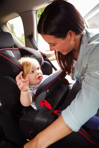 Mother Putting Daughter In Safety Seat — Stock Photo, Image